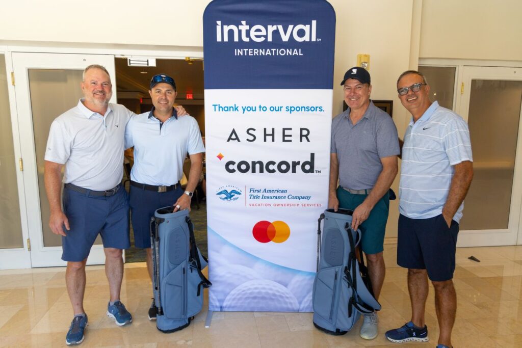 four men standing by sponsors sign