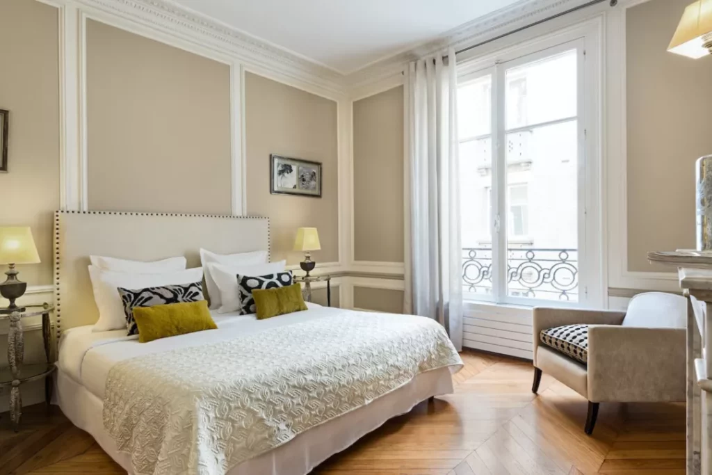 bedroom with king-sized bed, chair, and large window opening to European balcony