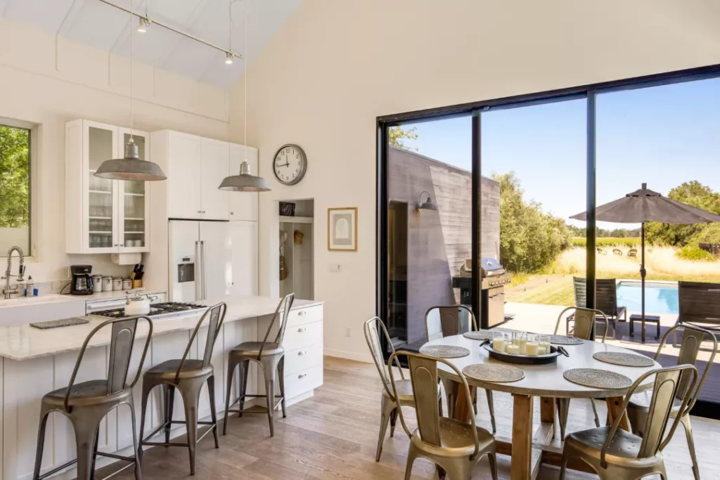 open kitchen with table and daytime view of patio and pool